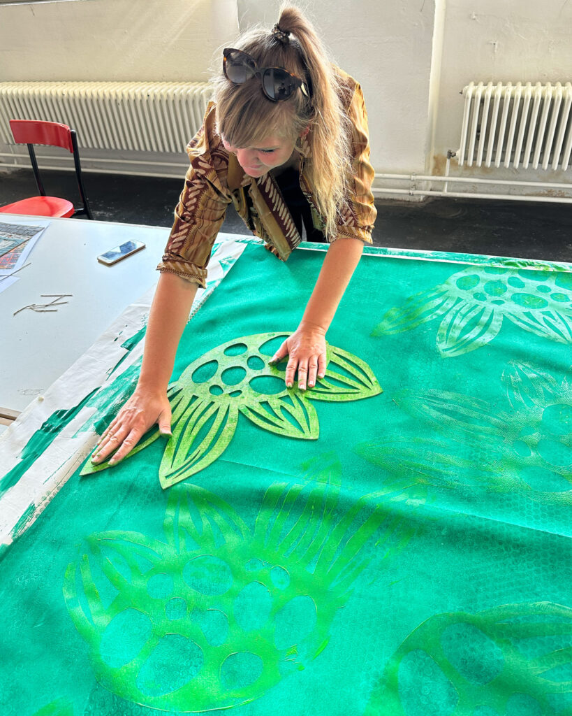 Caro bringt den Stempel auf ihr großes Format, das sie vorher dunkelgrün grundiert hat.