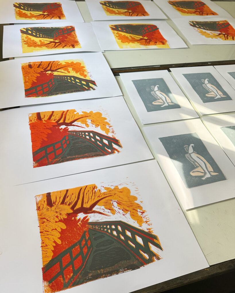 Die Drucke von Caro mit dem Ufer der Rednits und eine Person von Bianca liegen zum Trocknen auf dem Tisch.