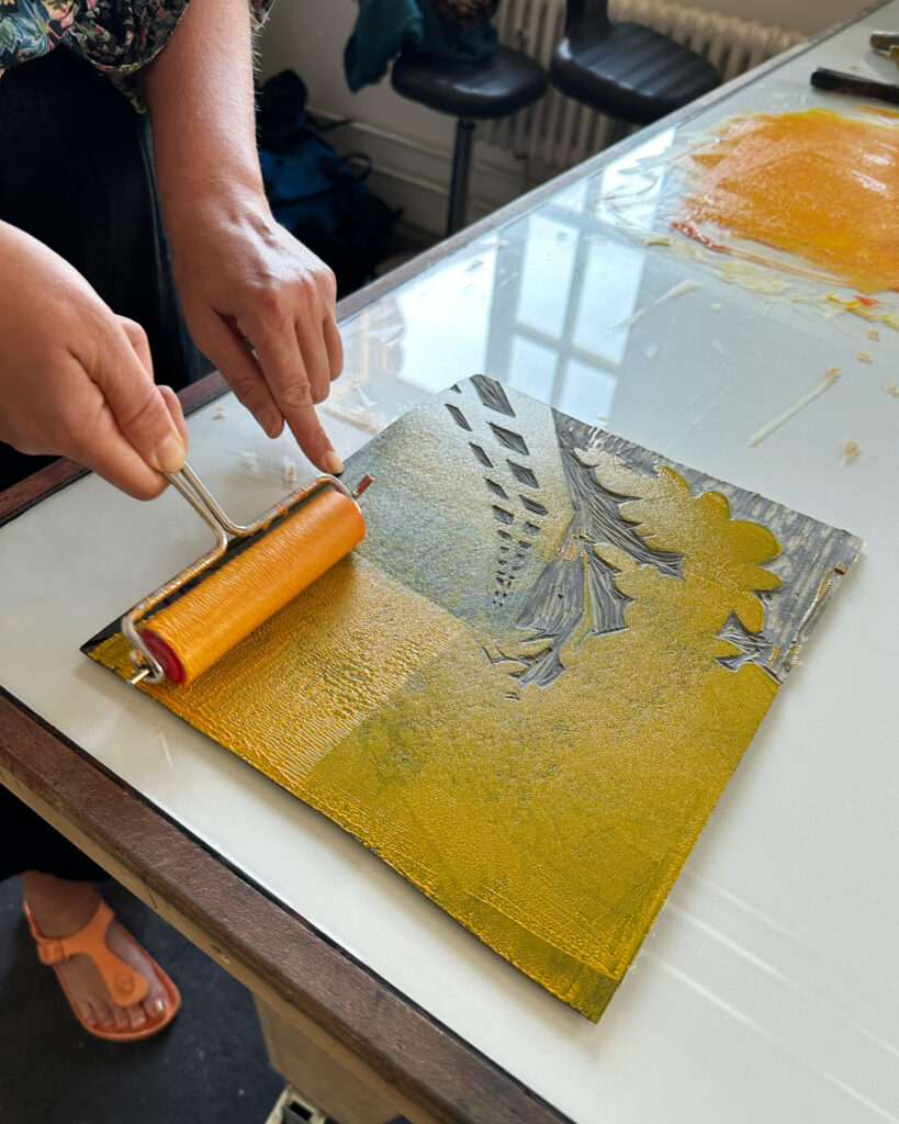 Caro färbt ihre Druckplatte mit dem Motiv der Rednitz in einem kräftigen Gelb ein.