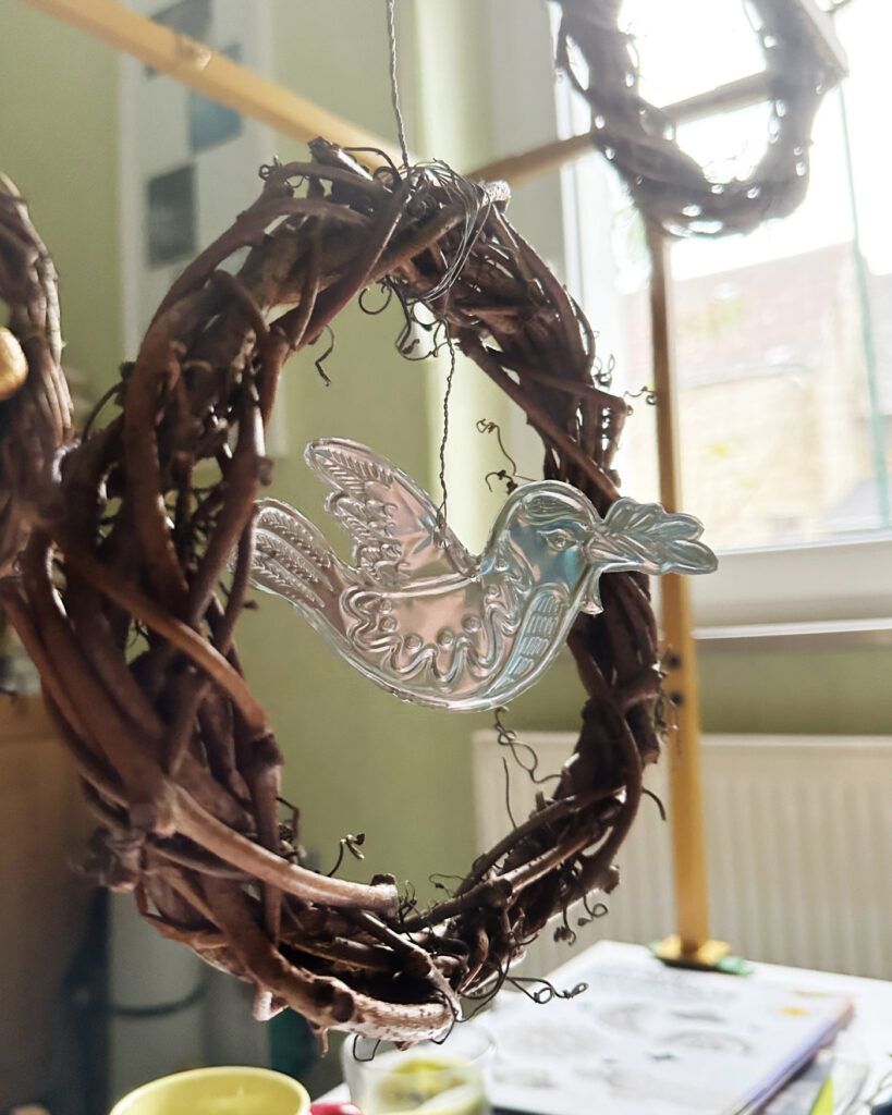 Eine kleine Friedenstaube aus silberner Prägefolie ist im Naturkranz aus Wildem Wein befestigt.