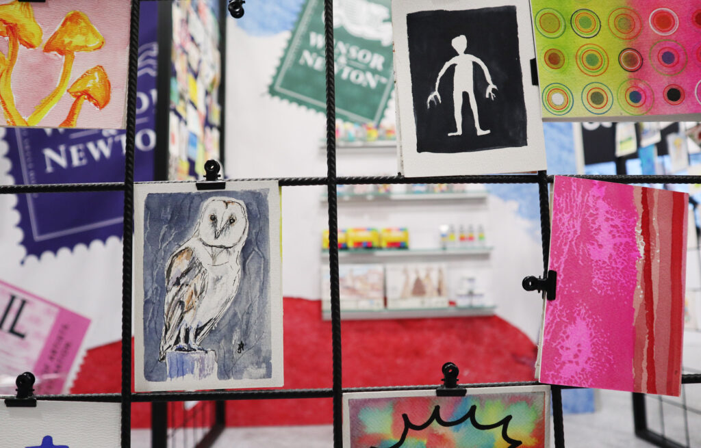 Mitmach-Aktion bei Winsor and Newton mit Postkarten, die an einer Gitterwand ausgestellt wurden.